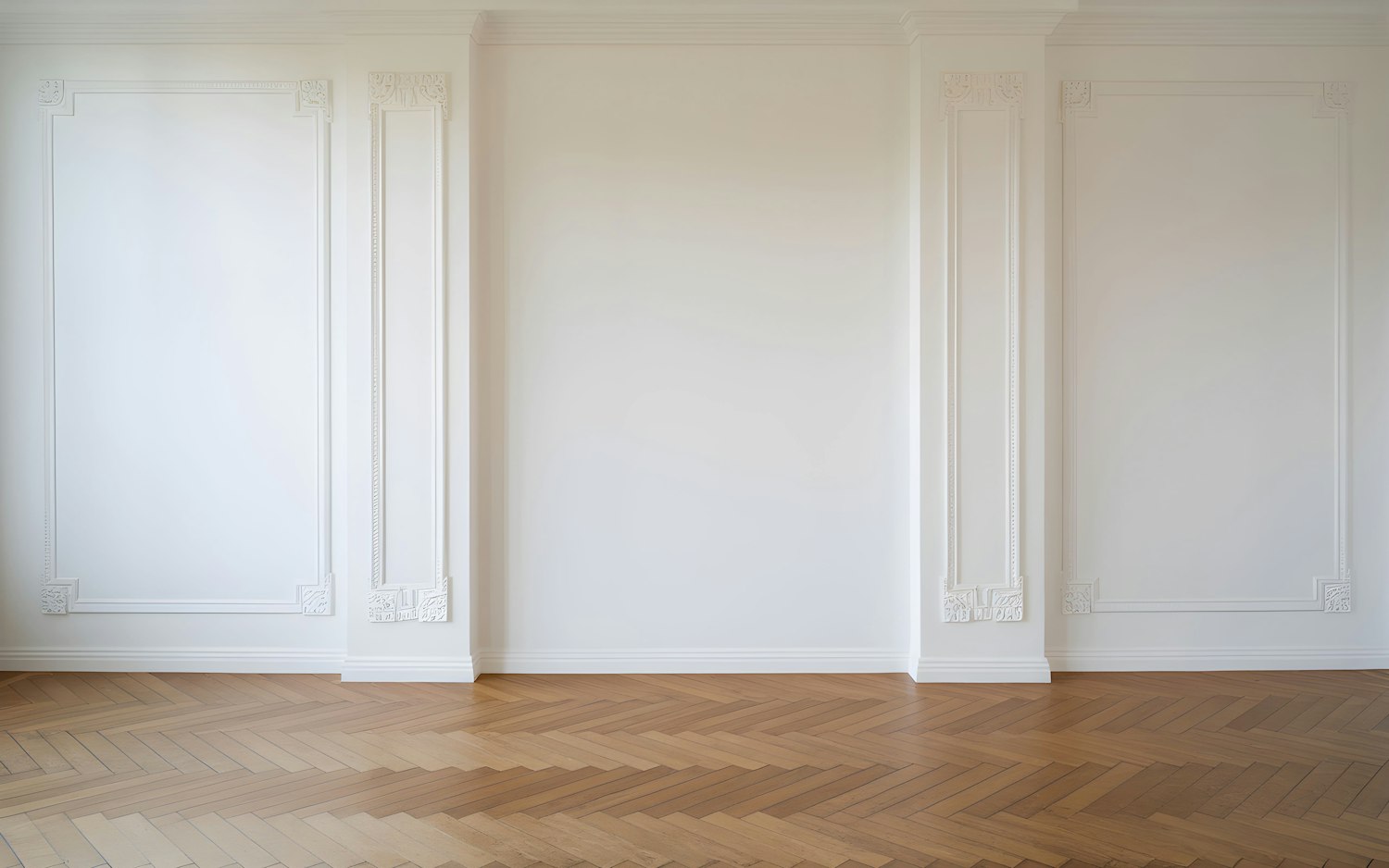 Interior with white walls, detailed molding and herringbone floors.